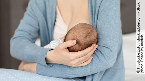 Unrecognizable Mother Holding And Breastfeeding Her Newborn Baby Eine Mutter hält ihr Baby im Arm und stillt.