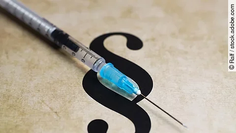 Closeup of paragraph symbol with vaccination syringe - mandatory
