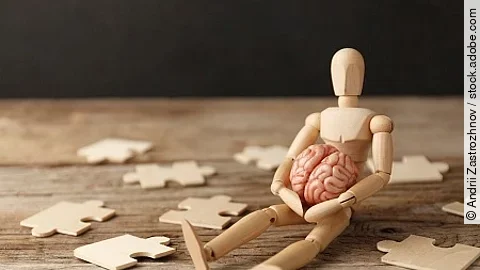 Toy man sits depressed with a puzzle. Despair and desolation. Co