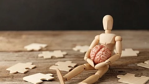 Toy man sits depressed with a puzzle. Despair and desolation. Co