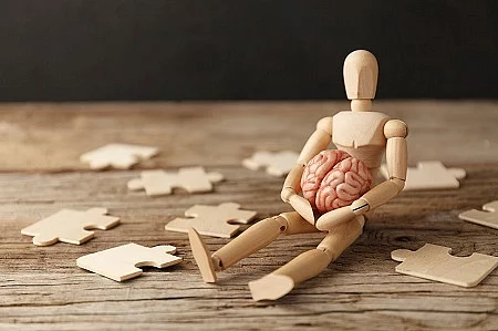 Toy man sits depressed with a puzzle. Despair and desolation. Co