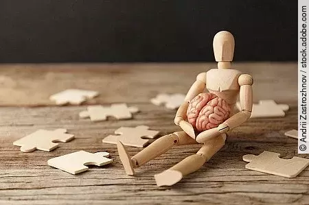 Toy man sits depressed with a puzzle. Despair and desolation. Co