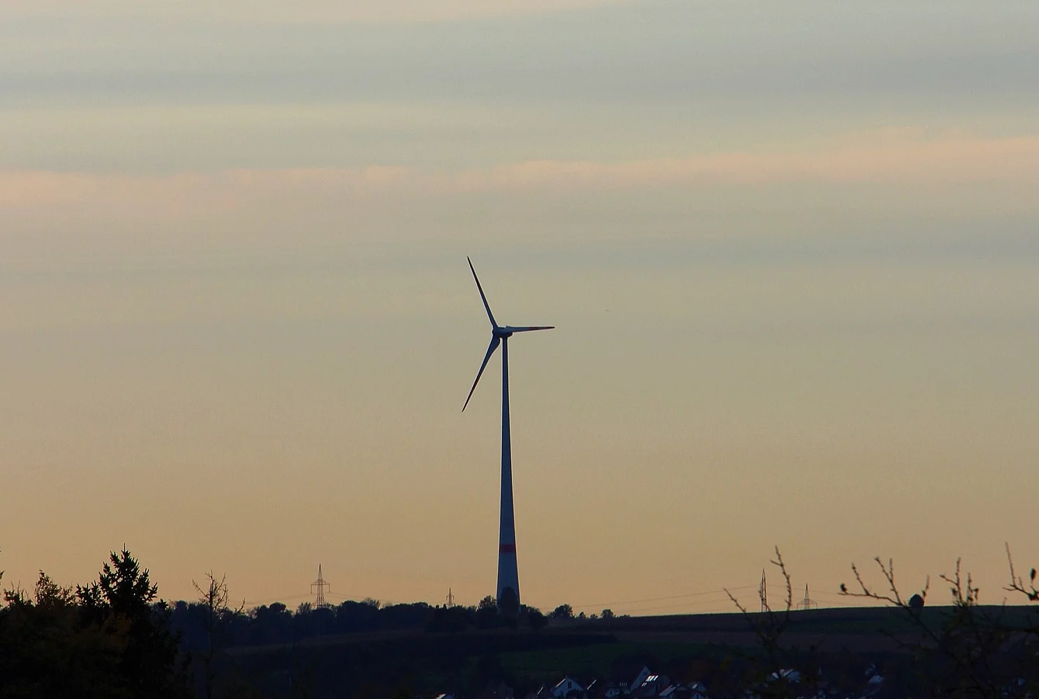 Eine einzelne Windkraftanlage steht in der Landschaft.