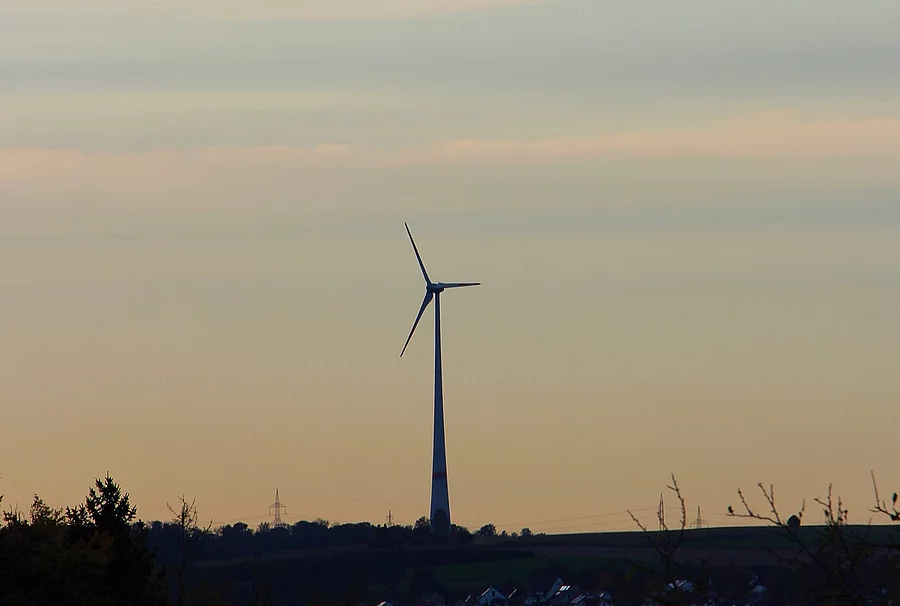 Eine einzelne Windkraftanlage steht in der Landschaft.