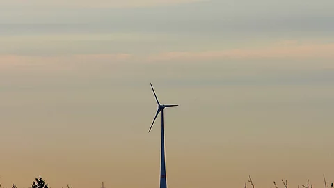 Eine einzelne Windkraftanlage steht in der Landschaft.