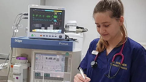 Corinne Leiner bearbeitet das Narkoseprotokoll für die nächste OP. Neben ihr steht das Inhalationsnarkosegerät mit Monitor.