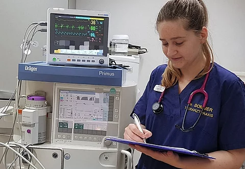 Corinne Leiner bearbeitet das Narkoseprotokoll für die nächste OP. Neben ihr steht das Inhalationsnarkosegerät mit Monitor.