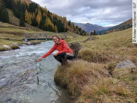 SLF-Hydrologin Amber van Hamel hält einen Sensor in den Dischmabach bei Davos.