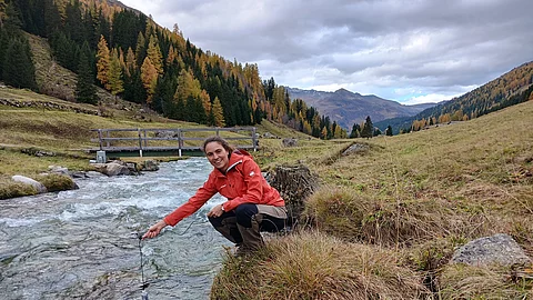 SLF-Hydrologin Amber van Hamel hält einen Sensor in den Dischmabach bei Davos.