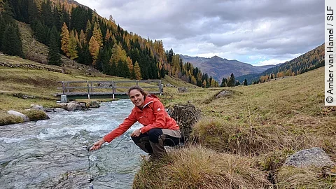 SLF-Hydrologin Amber van Hamel hält einen Sensor in den Dischmabach bei Davos.