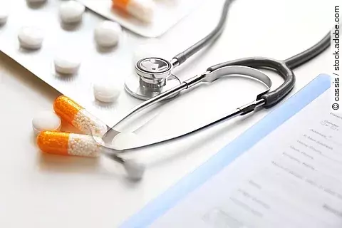 Auf einem Tische liegen verschiedene Medikamente und ein Stethoskop. 