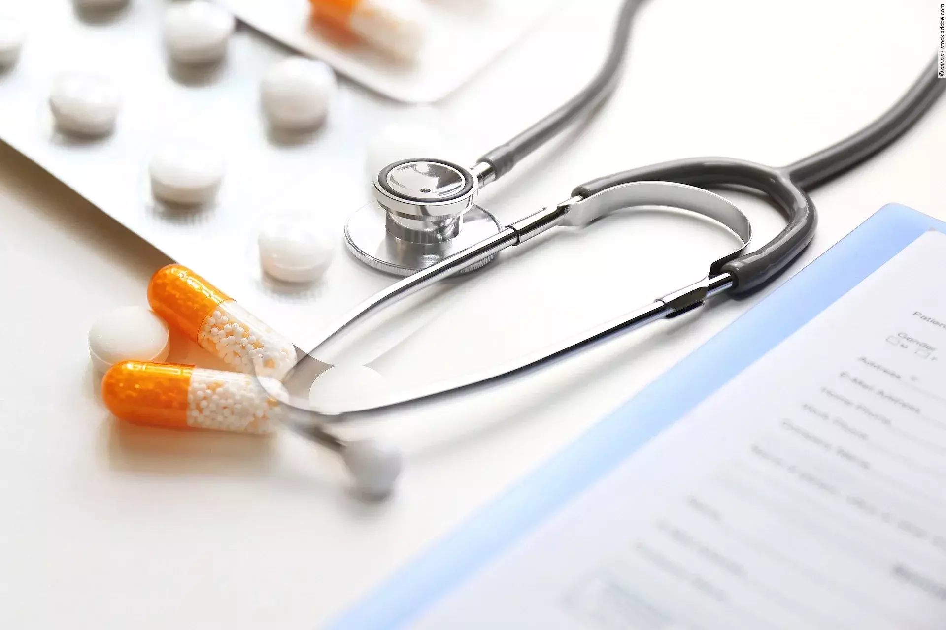 Auf einem Tische liegen verschiedene Medikamente und ein Stethoskop. 
