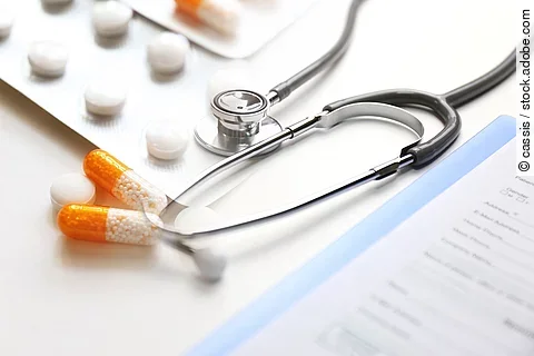 Auf einem Tische liegen verschiedene Medikamente und ein Stethoskop. 