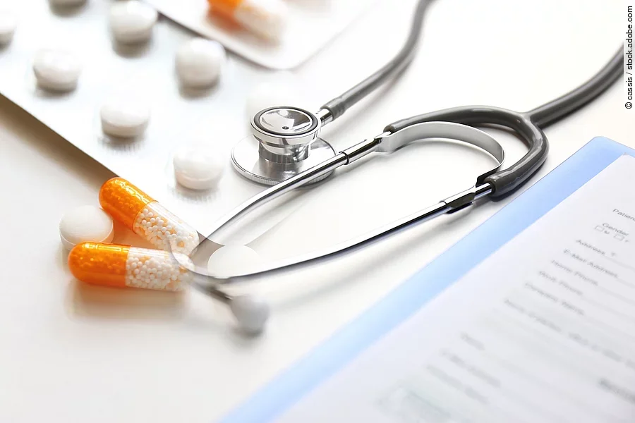 Auf einem Tische liegen verschiedene Medikamente und ein Stethoskop. 