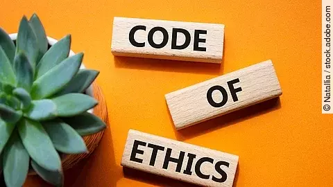 Auf einem orangenen Boden liegen 3 Holzklötze mit der Aufschrift Code of Ethics. Im linken Teil des Bildes steht eine Pflanze.