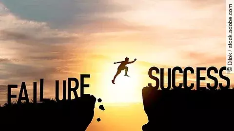 Ein Mensch springt von einer Klippe zu einer anderen - von Scheitern zu Erfolg. Im Hintergrund geht gerade die Sonne unter.