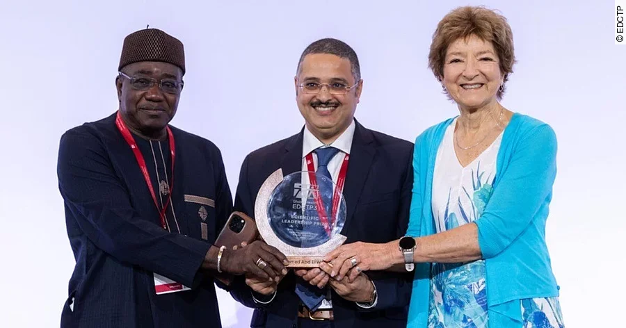 Der Tierarzt Dr. Ahmed El Wahed trägt einen Anzug bei der Preisverleihung und steht mit dem Preis in den Händen zwischen einem Mann und einer Frau. Der Tierarzt Dr. Ahmed El Wahed trägt einen Anzug bei der Preisverleihung und steht mit dem Preis in den Händen zwischen einem Mann und einer Frau.