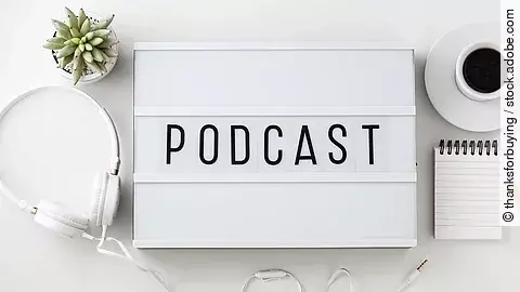Weiße Box mit dem Schriftzug "Podcast". Daneben liegen Kopfhörer.