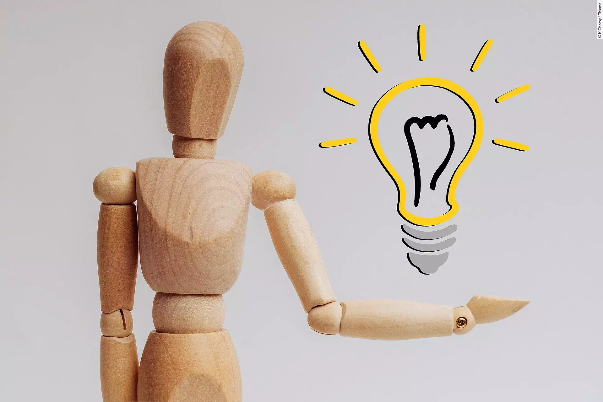 Eine Holzpuppe mit beweglichen Gelenken hält ihren linken Arm abgewinkelt vom Körper weg. Darüber schwebt eine leuchtende Glühbirne.