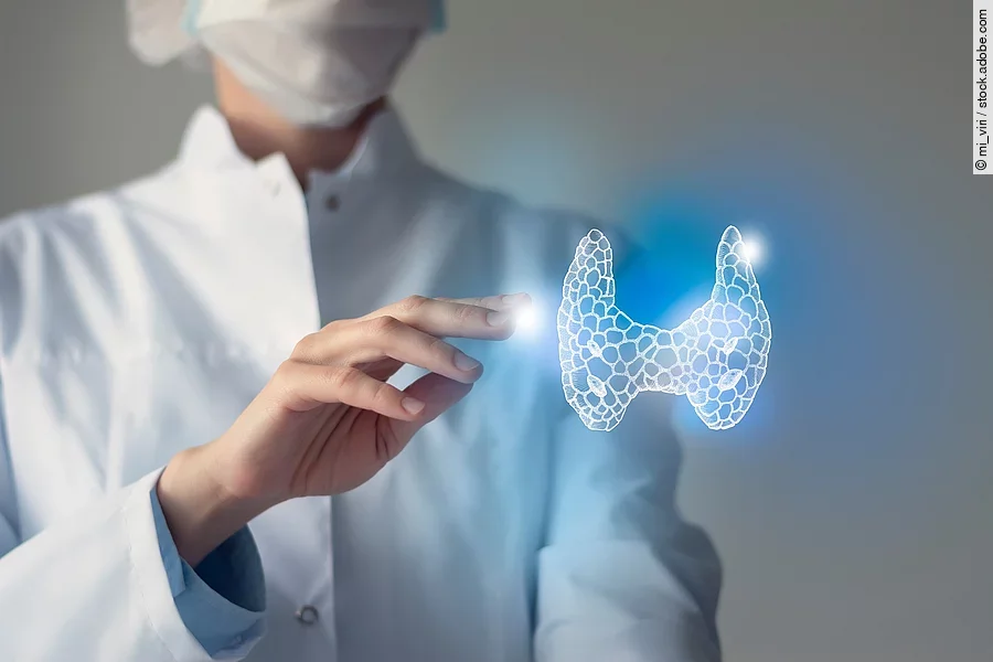 Arzt streckt seine Hand nach 3D-Illustration einer Schilddrüse aus.