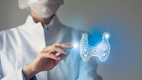 Arzt streckt seine Hand nach 3D-Illustration einer Schilddrüse aus.