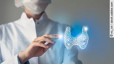 Arzt streckt seine Hand nach 3D-Illustration einer Schilddrüse aus.