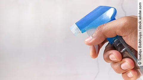 Nahaufnahme von einer Hand in der eine Sprühflasche gehalten wird.