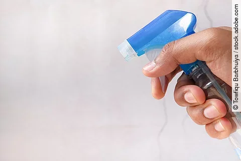 Nahaufnahme von einer Hand in der eine Sprühflasche gehalten wird.