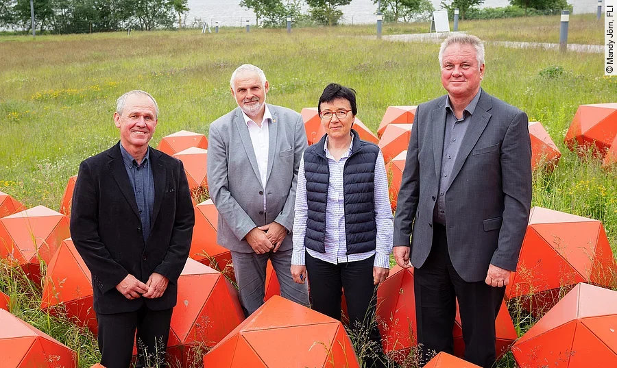 Der wiedergewählte Vorstand des FLI und die Präsidentin des Instituts posieren für die Kamera zwischen roten Skulpturen.