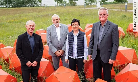 Der wiedergewählte Vorstand des FLI und die Präsidentin des Instituts posieren für die Kamera zwischen roten Skulpturen.