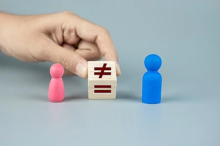 Hand change cube block of unequal to a equal sign between Pink Women and Blue Men wooden symbol. gender equality concept