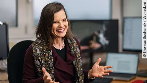 Frau Sonja Hartnack im Gespräch in einem Büro. Im Hintergrund sieht man einen Laptop und Bildschirme.