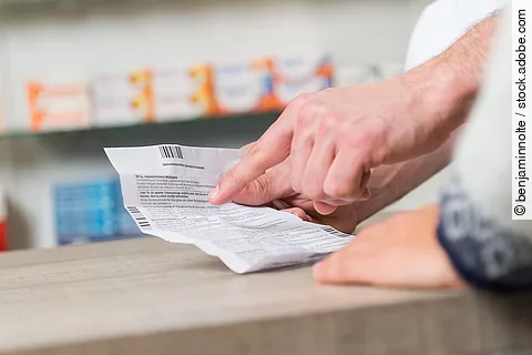 Apotheker erklärt einem Kunden einen Beipackzettel.