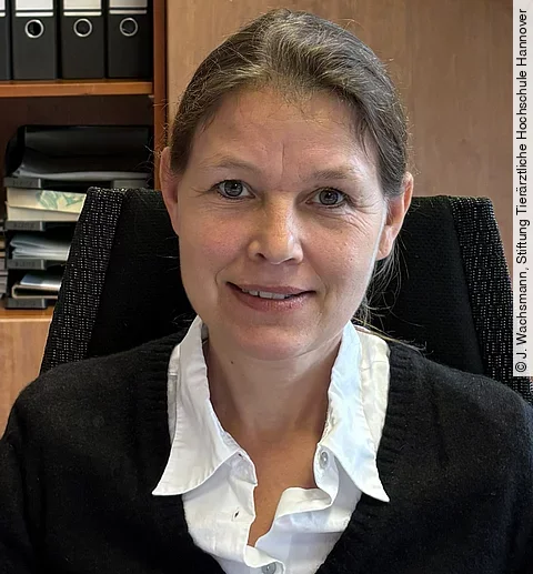 Aufnahme von Frau Prof. Dr. Strube. Sie sitzt in einem Büro und schaut freundlich in die Kamera. Ihre Haare sind zusammengebunden 