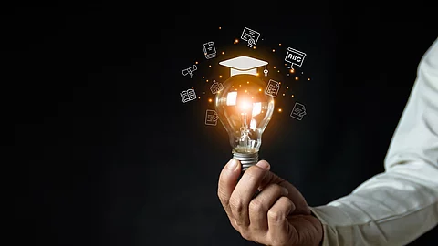 a man holding a light bulb showing his graduation cap internet e
