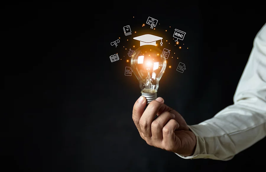 a man holding a light bulb showing his graduation cap internet e