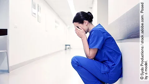 sad or crying female nurse at hospital corridor