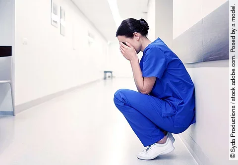 sad or crying female nurse at hospital corridor