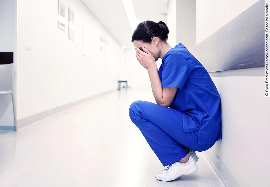 sad or crying female nurse at hospital corridor