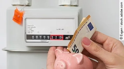Energy saving concept. Woman's hand inserting Euro cash in piggy