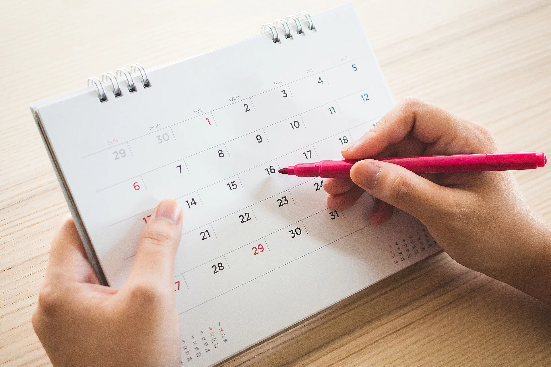 Eine Person hält einen Stift auf einen Kalender.