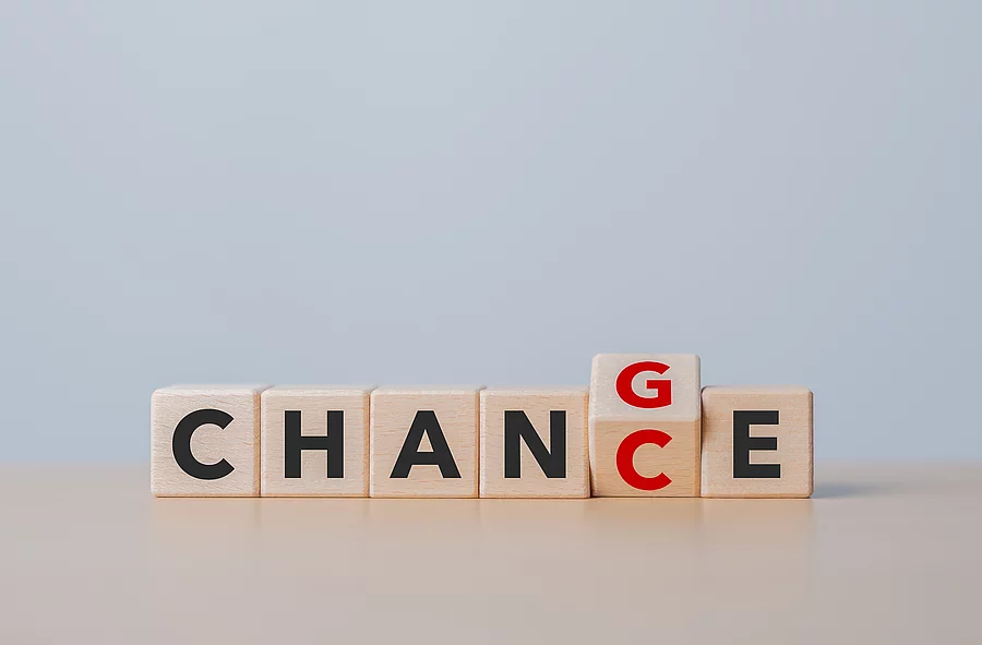 Sechs Buchstaben auf Holzklötzen ergeben das Word Change wobei das G zu einem C gewendet wird.