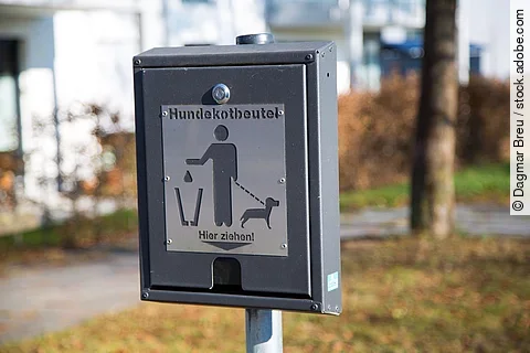 Eine Kotbeutelspender hängt in Wohnanlage und weist darauf hin, dass man die Hinterlassenschaften seines Hundes entfernt soll.