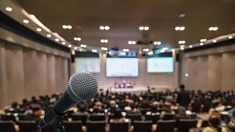 Microphone over the Abstract blurred photo of conference hall or