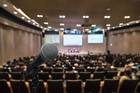 Microphone over the Abstract blurred photo of conference hall or
