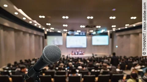 Microphone over the Abstract blurred photo of conference hall or