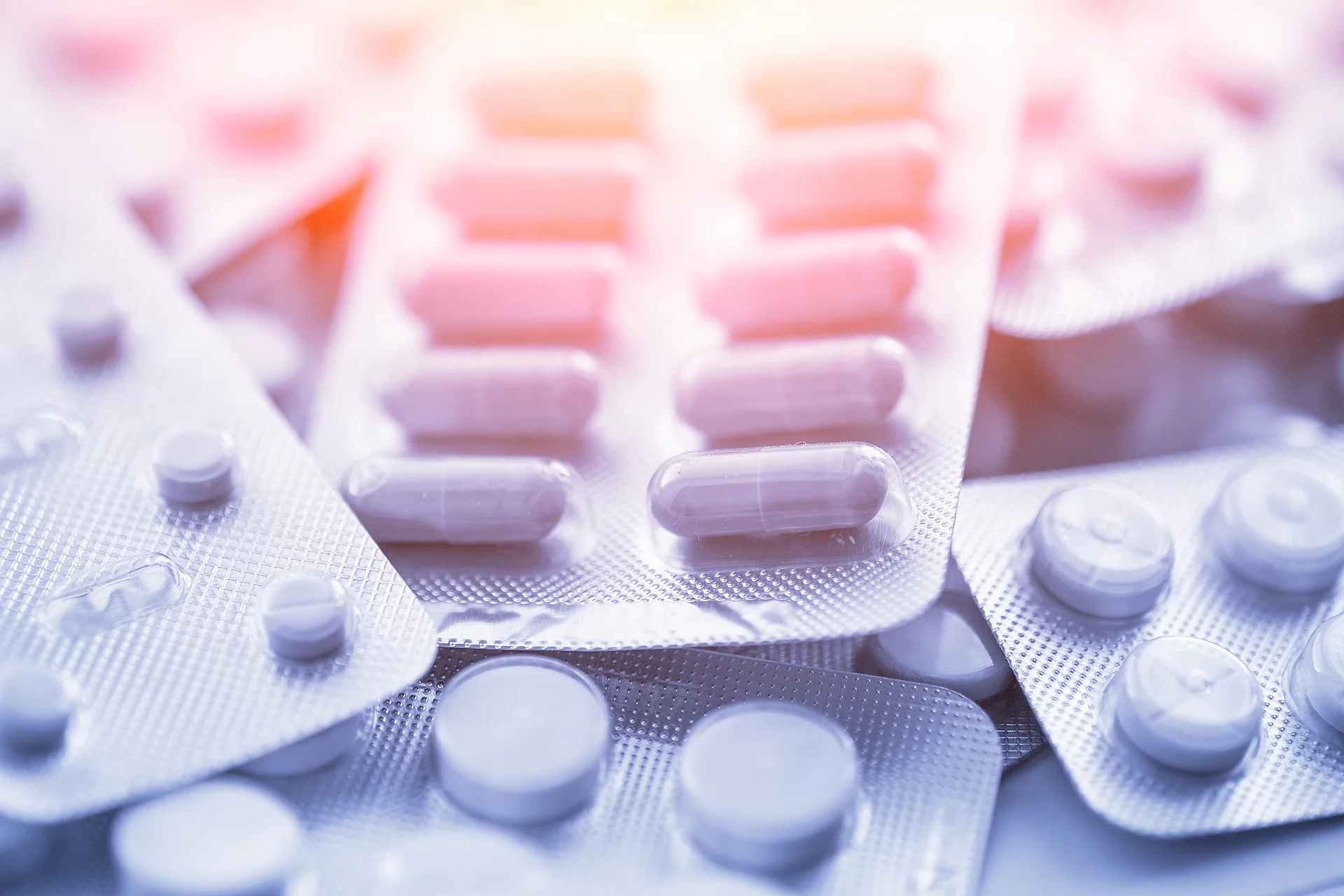 Verschiedene Arzneimittel liegen übereinander. Darunter sind Tabletten und Kapseln verpackt in weißen Blistern.