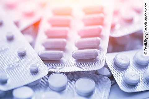 Verschiedene Arzneimittel liegen übereinander. Darunter sind Tabletten und Kapseln verpackt in weißen Blistern.
