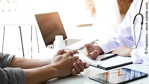 Zwei Personen sitzen an einem Tisch gegenüber und sind in einem Gespräch.