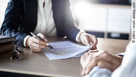 Zwei Business-Personen diskutieren über ein Dokument.